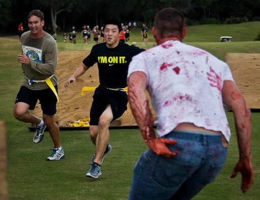 Runners try to avoid the zombies within the wooden barriers set up for the 2nd Annual Zombie Run Oct. 26 at the Eglin Air Force Base golf course.  More than 500 people attempted to outrun zombies and maneuver through various obstacles along the four-mile course.  (U.S. Air Force photo/Samuel King Jr.)