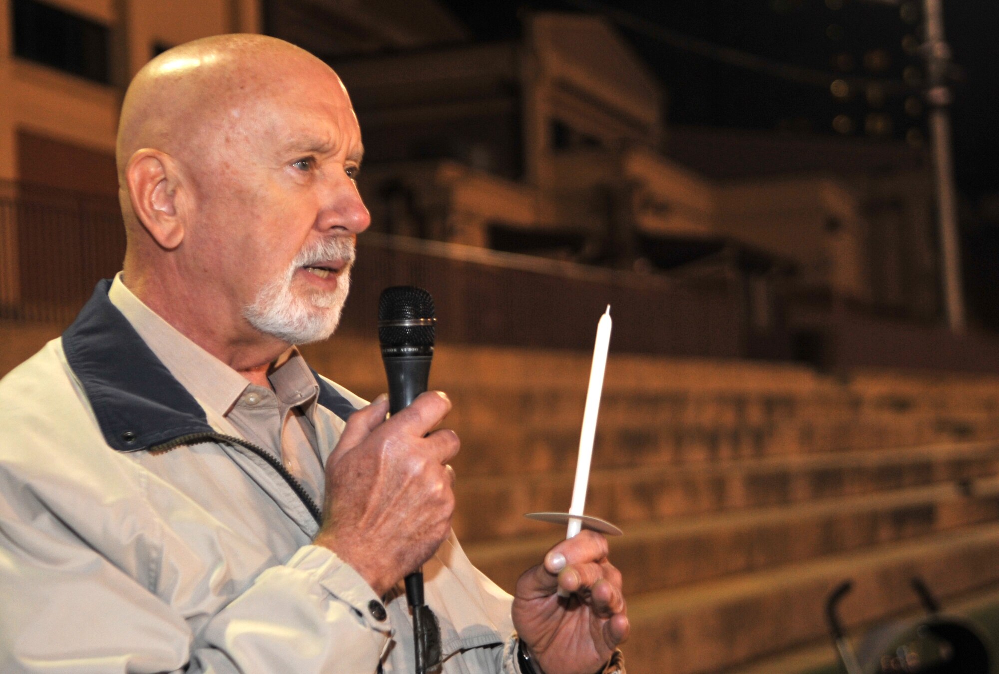 Carl Neighbors, 51st Medical Operations Squadron Family Advocacy intervention specialist, addresses participants of a candlelight vigil held for Breast Cancer and Domestic Violence Awareness Month on the Osan High School football field at Osan Air Base, Republic of Korea, Oct. 26, 2013. Neighbors encouraged everyone present to reach out to affected families and to help them find an outlet for their pain. (U.S. Air Force photo/Airman 1st Class Ashley J. Thum)