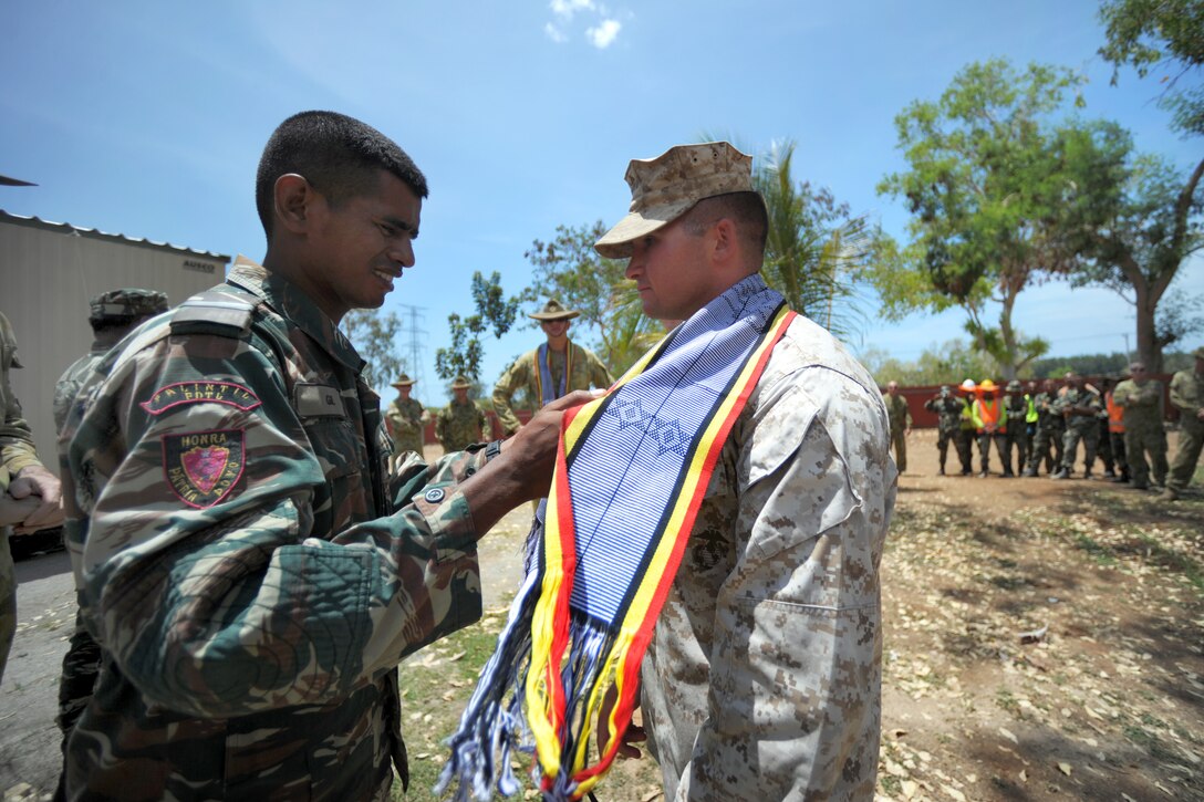 U.S. Marine Corps 1st Lt. Richard Fitzgerald, right, receives a traditional tais, or scarf, from a Timor-Leste defense force troop during an appreciation ceremony for Sapper 13 participants in Dili, Timor-Leste, Oct. 25, 2013. Fitzgerald, a platoon commander, is assigned to the 9 Engineering Support Battalion, Engineering Alpha Company. 
