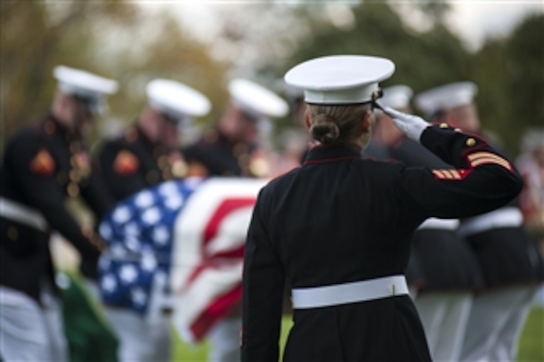 U.S. Marine Sgt. Katie Maynard salutes as a casket is lowered during a funeral ceremony at Arlington National Cemetery, Va., on Oct. 24.  The ceremony was held for a group of six Marines who died in a CH-53 helicopter crash in Afghanistan on January 19, 2012.  