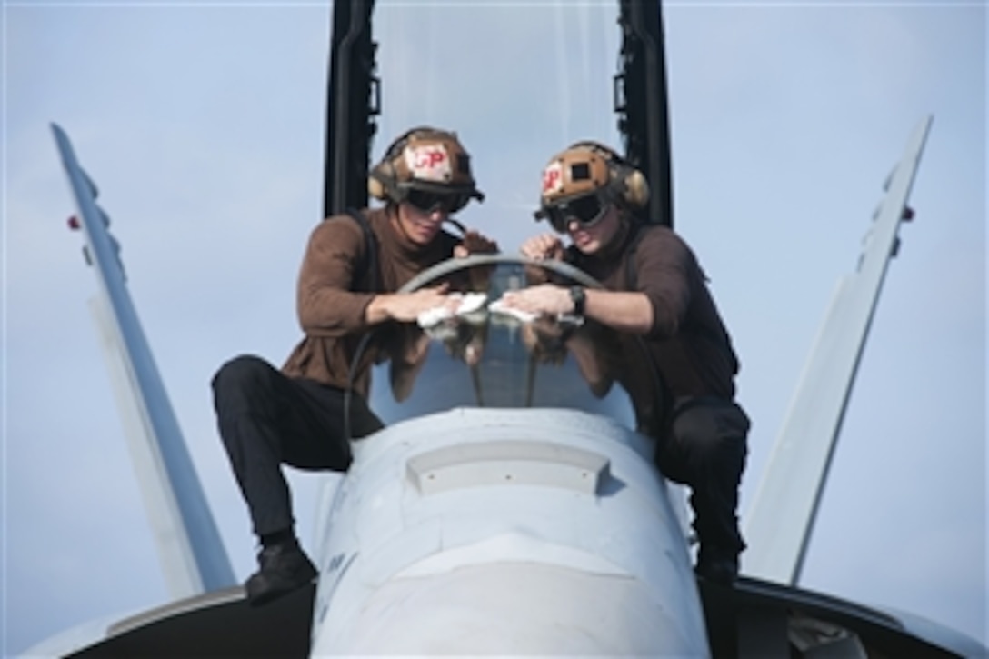 U.S. Navy Airmen Adam Kelty, left, and Stephen Back polish the canopy of an EA-18G Growler parked on the flight deck of the aircraft carrier USS Harry S. Truman (CVN 75) as the ship operates in the Gulf of Oman on Oct. 23, 2013.  The Harry S. Truman Carrier Strike Group is deployed to the U.S. 5th Fleet area of responsibility to conduct maritime security operations and theater security cooperation efforts.  Kelty and Back are assigned to Electronic Attack Squadron 130.  