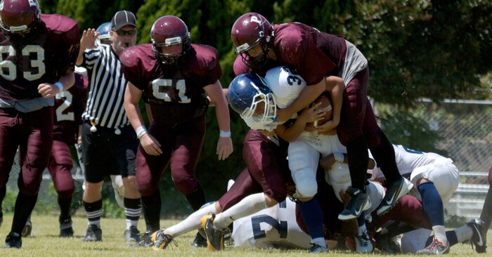 Charlie Van Allen, a Matthew C. Perry High School Samurai running back and linebacker, tackles a Sotoku High School Fighting Ducks running back during a scrimmage game at the M. C. Perry football field here Aug. 19, 2012. “I thought we were quite competitive, considering they have been practicing for a year and some of those kids have been together for three years,” said Frank Macias, Samurai head coach. “They play semi-pro and college teams as well. We are a brand new program. For most of these kids, this is the first time they have ever hit somebody.”