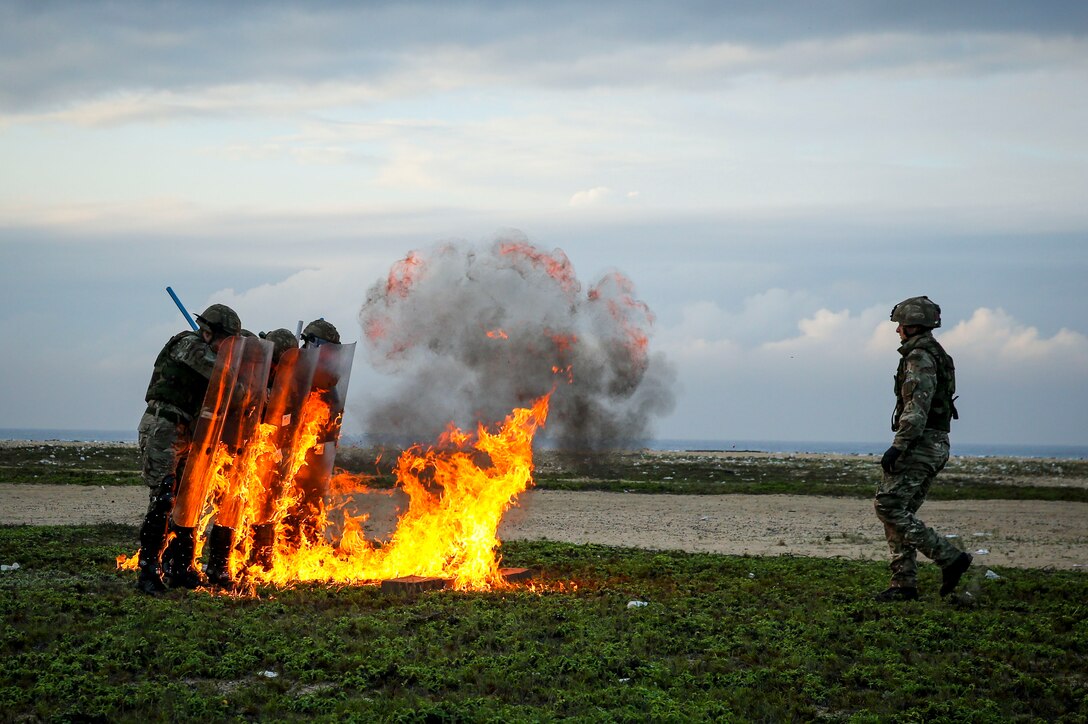 British Royal Marines, in the true spirit of "train as they fight," demonstrate proper riot control techniques October 18, 2013 as Molotov cocktails are used against the line.  United States Marines with Africa Partnership Station participated in a training exercise focusing on riot control, riverine operations, ambush reaction drills and more. Each exercise, led by British Marine forces, challenged the Marines through different scenarios focusing on all aspects of military tactics. APS is an international security cooperation initiative, facilitated by U.S. Naval Forces Africa, aimed at strengthening global maritime partnerships through training and collaborative activities in order to improve maritime safety and security in Africa. (Official U.S. Marine Corps photo by Sgt. Marco Mancha)