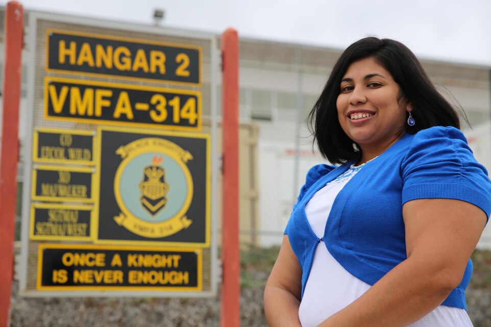 Maricella Villegas, a family readiness assistant with Marine Fighter Attack Squadron 314, poses with her husband’s squadron’s signage aboard Marine Corps Air Station Miramar, Calif., Oct. 24. Villegas is highlighted as part of the Committed and Engaged Spouse campaign.