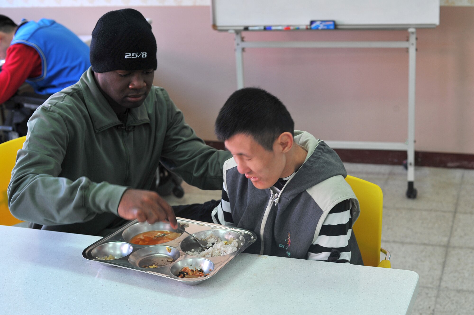 Airman 1st Class Thomas Walker, 51st Logistics Readiness Squadron vehicle operator, prepares to feed a blind resident of the Seongsimdongwon Group Home for the disabled in Osan City, Republic of Korea, Oct. 27, 2013. The Osan Air Base Company Grade Officer’s Council and members of the 51st Fighter Wing Staff Agencies combined forces to bring Halloween treats and spend time with residents and students with special needs at the group home. (U.S. Air Force photo/Staff Sgt. Emerson Nuñez)