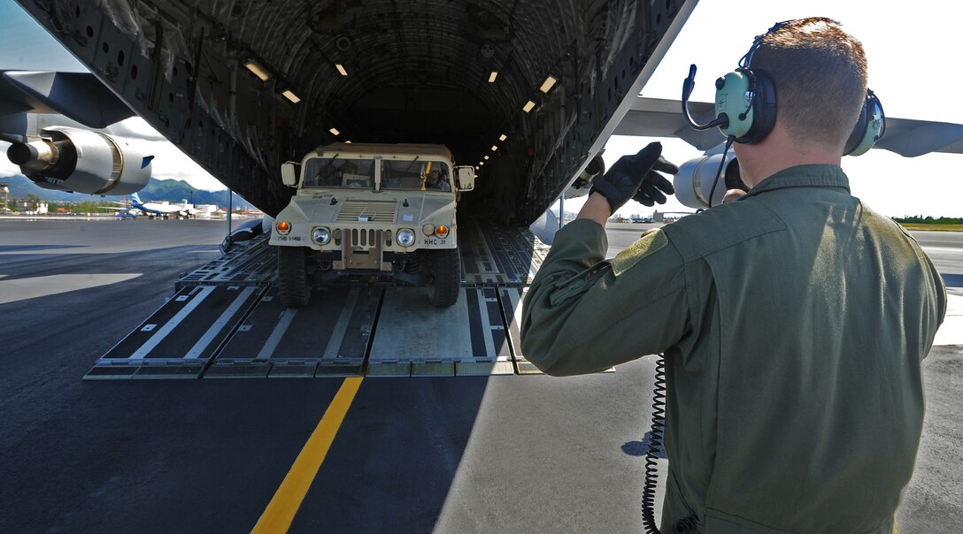 Senior Airman Jacob Willenborg, 535th Airlift Squadron loadmaster, guides a Stryker and trailer aboard a C-17 Globemaster III at Joint Base Pearl Harbor Hickam, Hawaii, Oct. 17, 2013. The vehicle was loaded as part of a validation exercise, which tested the 2nd Stryker Brigade Combat Team's ability to load their interim armored vehicles onto C-17s and fly them to the Pohakuloa Training Area in Kona, Hawaii. (U.S. Air Force photo/Tech. Sgt. Jerome S. Tayborn) 