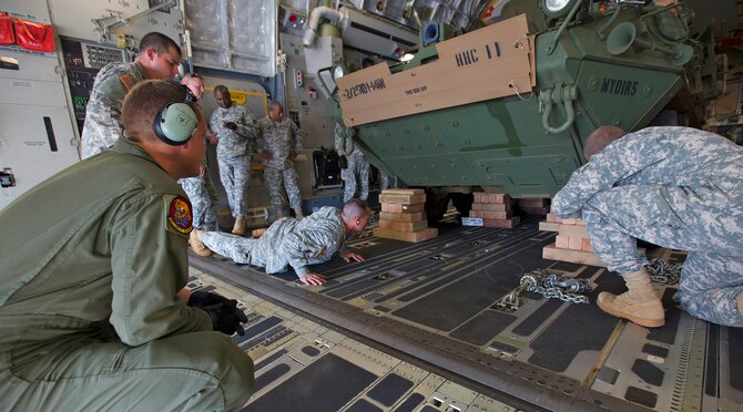 Senior Airman Jacob Willenborg, 535th Airlift Squadron loadmaster, left, helps secure the load of a Stryker medical evacuation vehicle assigned to the 1-14 Infantry Battalion 2nd Stryker Brigade Combat Team, aboard a C-17 Globemaster III during a validation exercise on the flightline at Joint Base Pearl Harbor Hickam, Hawaii, Oct. 17, 2013. The Stryker is used to provide quick response maneuvering capability, enhanced survivability and lethality and expand fight versatility. (U.S. Air Force photo/Tech. Sgt. Jerome S. Tayborn)
