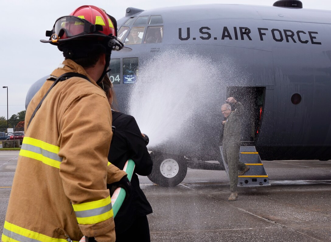 Assisted by a member of the Dobbins Fire Department, Col. Tim E. Tarchick, 94th Airlift Wing, commander receives the traditional hose down from wife, Cindee Tarchick during his finiflight at Dobbins Air Reserve Base, Ga. Oct. 28. Tarchick retires after 35.5 years of successful service. (U.S. Air Force photo/Don Peek)