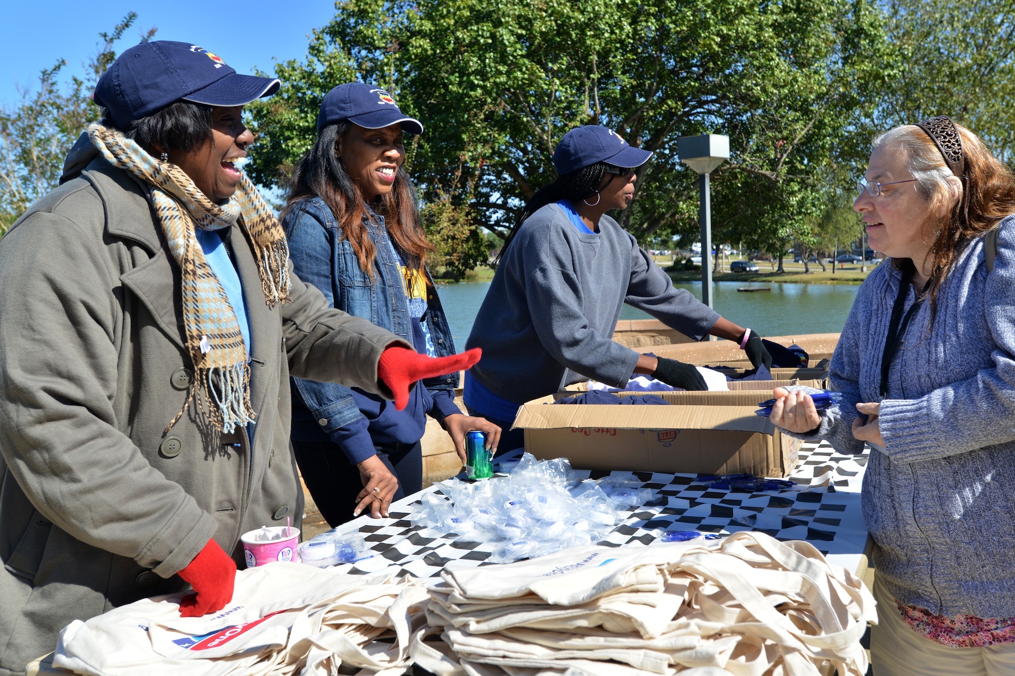 [From left] Zelda Williams, 20th Contracting Squadron contract specialist, Patrice Kornicky, 20th CS contracting intern, and Shaunannette Watson, 20th CS systems administrator and procurement technician, greet individuals passing by the gift table during an Ability One appreciation picnic, Shaw Air Force Base S.C., Oct. 25, 2013. The three women handed out free pens, hats and bags as a way of saying “thanks” to Ability One employees and their families. (U.S. Air Force photo by Airman 1st Class Jensen Stidham/Released)