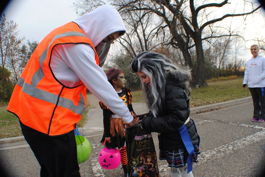 Trick-or-treaters receive candy for completing sections of the family fun run portion of the Zombie Run, held Oct. 26, 2013, on Grand Forks Air Force Base, N.D. The event, hosted by Chapter 964 of the Air Force Sergeants Association, was designed to encourage friendly interactions among participants. (U.S. Air Force photo/Staff Sgt. Luis Loza Gutierrez)