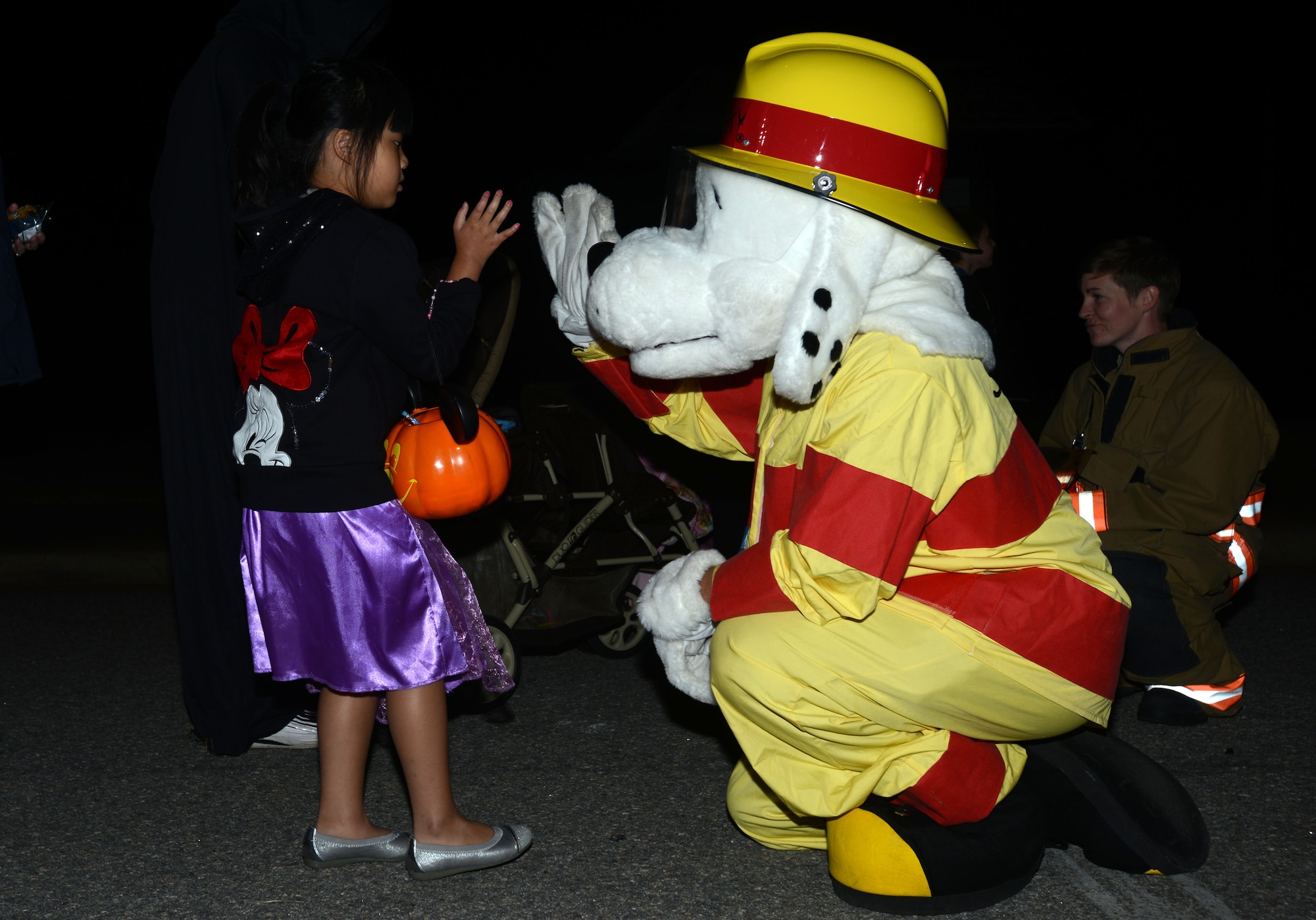 The 20th Civil Engineer Squadron fire department’s fire dog high-five’s a trick-or-treater at the final stop of this year’s Boo Bash and Trunk-or-Treating event Oct. 26, 2013, at Shaw Air Force Base, S.C. The evening’s festivities included trunk-or-treating, a carnival, an outdoor movie, and costume and trunk contests. This annual event is hosted to provide a safe Halloween experience for Team Shaw families. (U.S. Air Force photo by Senior Airman Laura L. Valentine/Released)