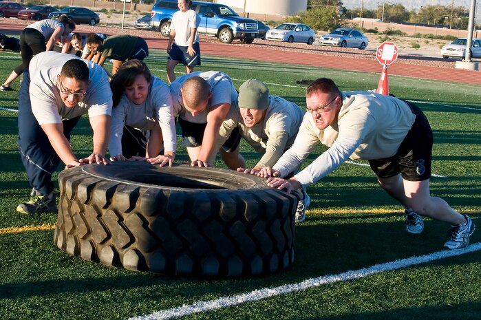 Airmen push a tire during a warrior trained fitness workout on the field behind the Warrior Fitness Center Oct. 22, 2013, at Nellis Air Force Base, Nev. Airmen worked as a team to either push or flip a rubber tire duringthe workout. Ben Booker, founder of Second Chance Lifestyle, led two workout sessions at 7 a.m. and 3:30 p.m. (U.S. Air Force photo by Senior Airman Matthew Lancaster)