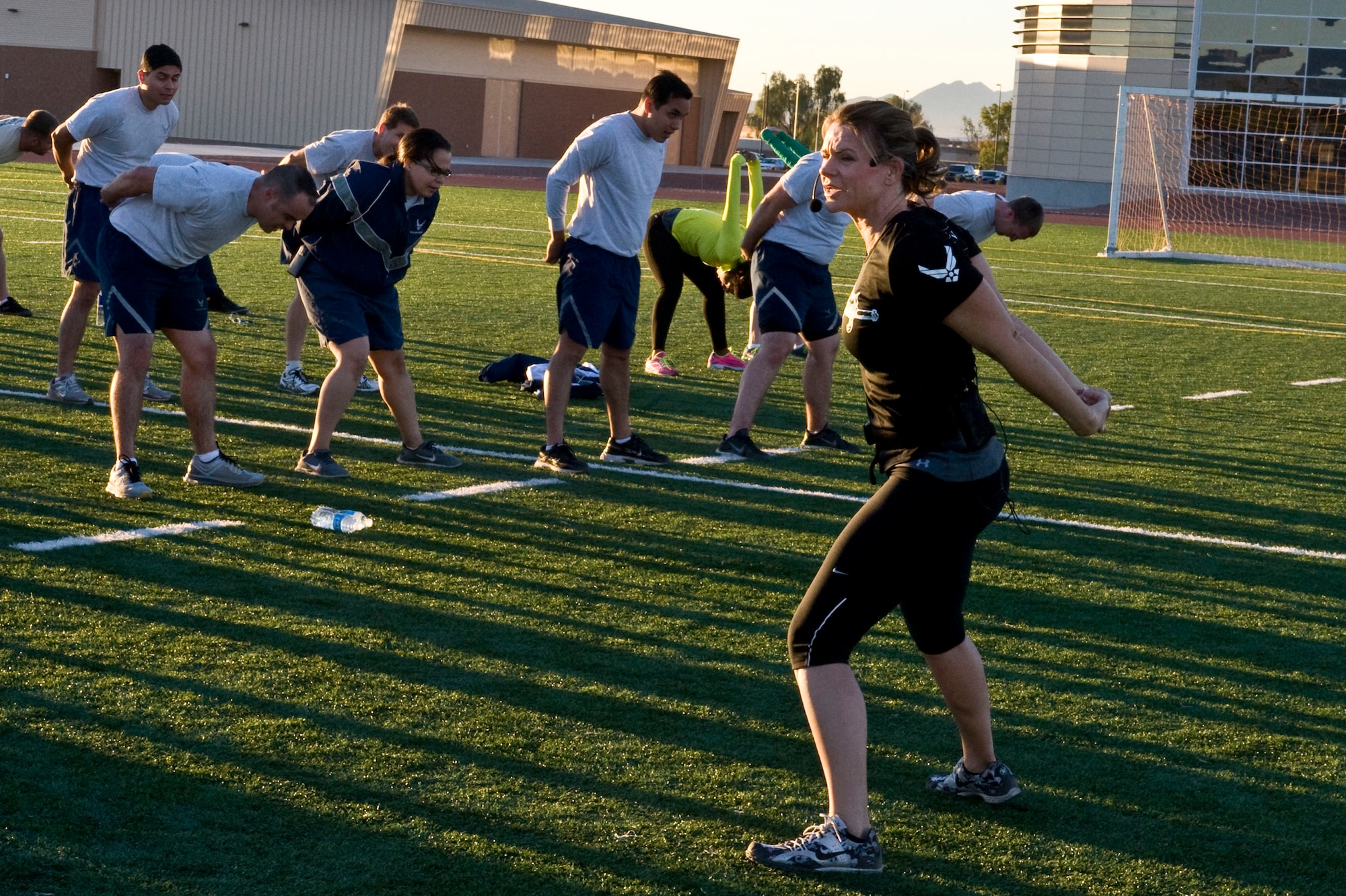 Missy Cornish, wife of Col. Barry Cornish, 99th Air Base Wing commander, leads stretches during a warrior trained fitness workout on the field at the track behind the Warrior Fitness Center Oct. 22, 2013, at Nellis Air Force Base, Nev. Participants warmed up and stretched before a workout led by Ben Booker, founder of Second Chance Lifestyle. (U.S. Air Force photo by Senior Airman Matthew Lancaster)