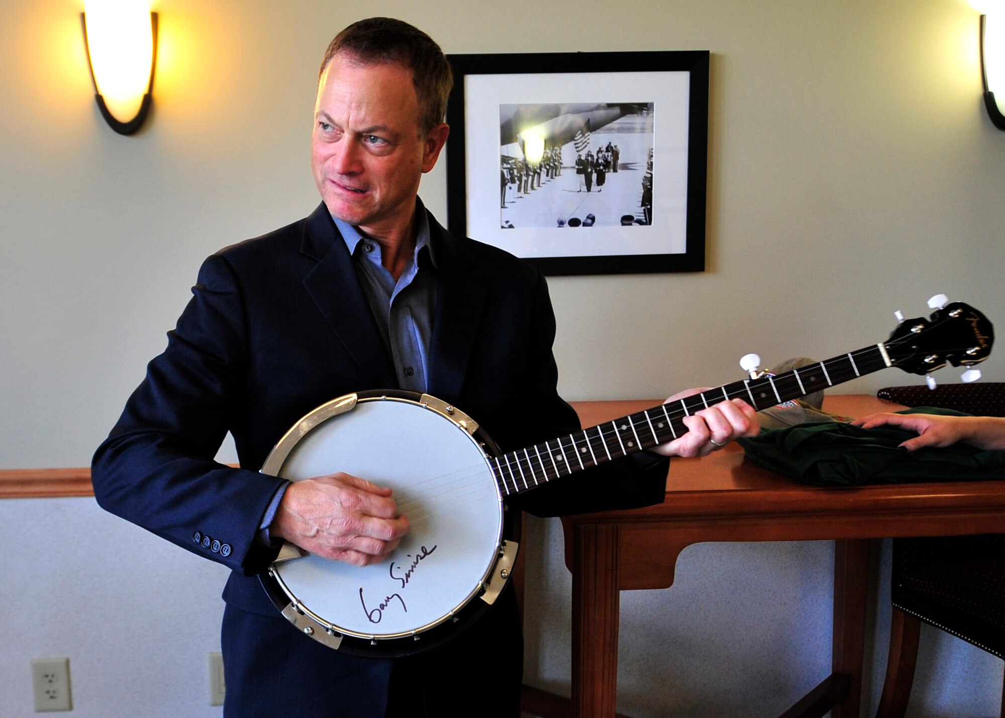 Gary Sinise plays a banjo that he autographed for Bruce Kmiec, USO Delaware programs manager, Oct. 24, 2013, at Dover Air Force Base, Del. Sinise, who is a star of both movies and TV, also formed his own band the “Lt. Dan Band,” named after his character in the movie Forrest Gump and plays to mainly military audiences. (U.S. Air Force photo/Tech. Sgt. Chuck Walker)