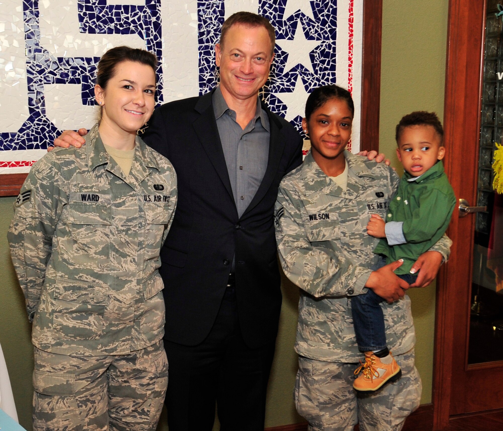 Gary Sinise poses for a picture with Senior Airman Theresa Ward, 436th Force Support Squadron fitness center and Senior Airman Calota Wilson, 436th FSS fitness center, and her son Jagger, Oct. 24, 2013, at the USO on Dover Air Force Base, Del. Sinise said he and his wife having family members in the military is the reason he has been a part of the USO since 2003. (U.S. Air Force photo/Tech. Sgt. Chuck Walker)