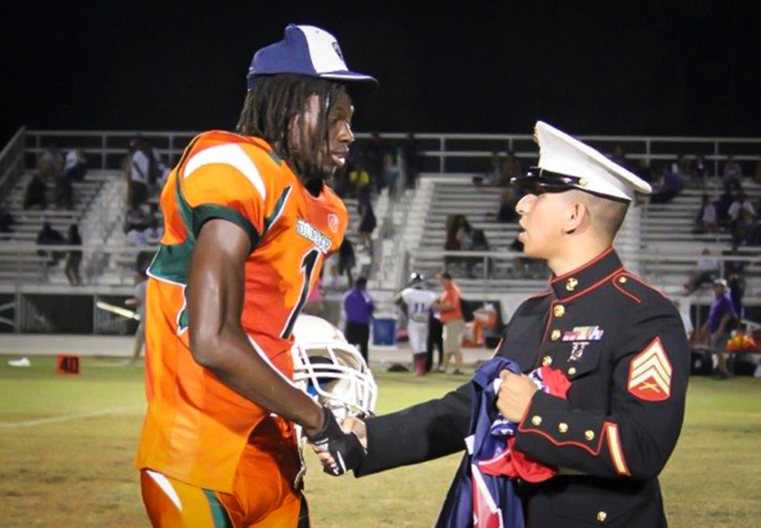 Marine Corps recruiter Sgt. Mario Sanchez with Recruiting Substation Fort Myers, Recruiting Statin Fort Lauderdale, Fla., presents a jersey to Ryeshene Bronson from Dunbar High School Oct. 11, 2013, for being selected to play in the Semper Fidelis All American Bowl. Bronson, a senior wide receiver at Dunbar, excels in the class room and is a prominent mentor in his community. Selected to play for his character as a whole, Bronson said he is excited about the opportunity and that he is "ready to go."   