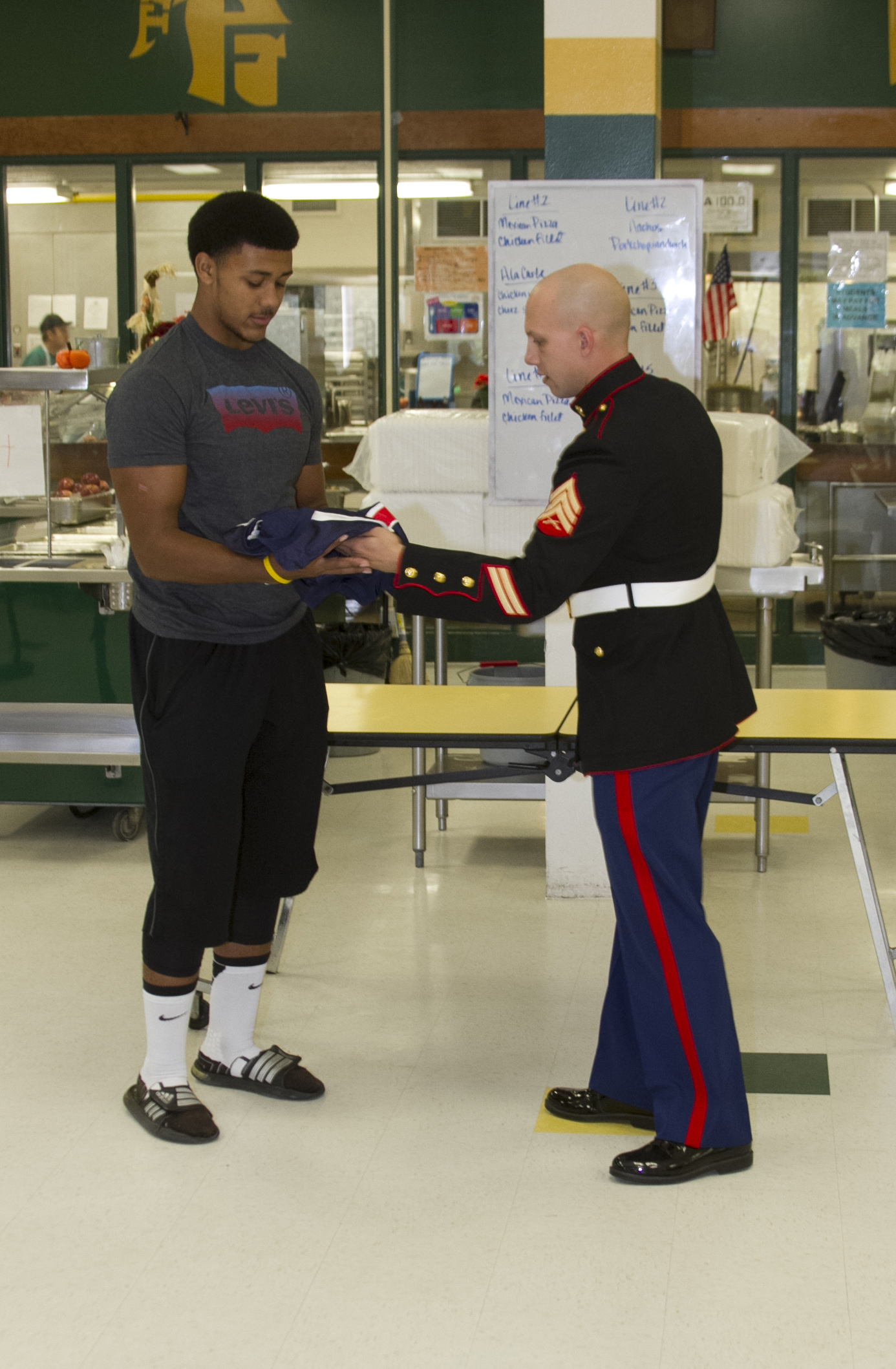U.S. Marine Corps Sgt. Matthew Pruitt, a recruiter with Marine Corps Recruiting Sub Station Fayetteville, presents Harold Landry, a defensive end for the Pine Forest High School football team, with a jersey during his Semper Fidelis All-American Bowl jersey presentation at Pine Forest High School in Fayetteville, N.C., Oct. 23, 2013. Landry was selected to play in the bowl for his skill as a defensive end, his academics and his leadership ability.  The Semper Fidelis All-American Bowl allows the Marine Corps to purposefully engage with well-rounded student athletes to share leadership lessons that will enable future success. It will be played on Jan. 5, 2014, in Carson City, Calif., and will be broadcast on Fox Sports 1. (U.S. Marine Corps photo by Sgt. Dwight A. Henderson/Released) 