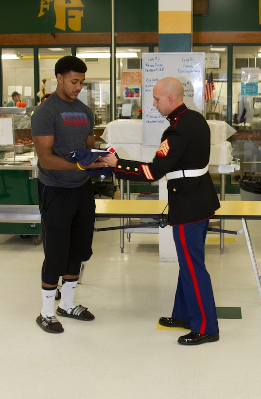 U.S. Marine Corps Sgt. Matthew Pruitt, a recruiter with Marine Corps Recruiting Sub Station Fayetteville, presents Harold Landry, a defensive end for the Pine Forest High School football team, with a jersey during his Semper Fidelis All-American Bowl jersey presentation at Pine Forest High School in Fayetteville, N.C., Oct. 23, 2013. Landry was selected to play in the bowl for his skill as a defensive end, his academics and his leadership ability.  The Semper Fidelis All-American Bowl allows the Marine Corps to purposefully engage with well-rounded student athletes to share leadership lessons that will enable future success. It will be played on Jan. 5, 2014, in Carson City, Calif., and will be broadcast on Fox Sports 1. (U.S. Marine Corps photo by Sgt. Dwight A. Henderson/Released) 