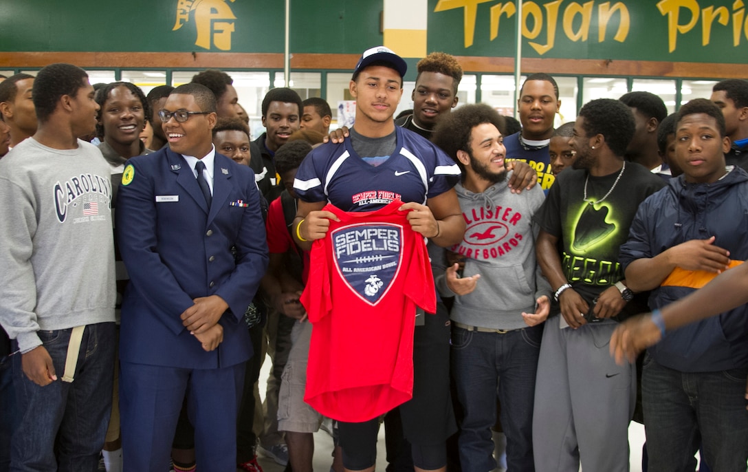 Harold Landry, center, a defensive end for the Pine Forest High School football team, poses for a picture with his teammates during his Semper Fidelis All-American Bowl jersey presentation at Pine Forest High School in Fayetteville, N.C., Oct. 23, 2013. Landry was selected to play in the bowl for his skill as a defensive end, his academics and his leadership ability.  The Semper Fidelis All-American Bowl allows the Marine Corps to purposefully engage with well-rounded student athletes to share leadership lessons that will enable future success. It will be played on Jan. 5, 2014, in Carson City, Calif., and will be broadcast on Fox Sports 1. (U.S. Marine Corps photo by Sgt. Dwight A. Henderson/Released) 