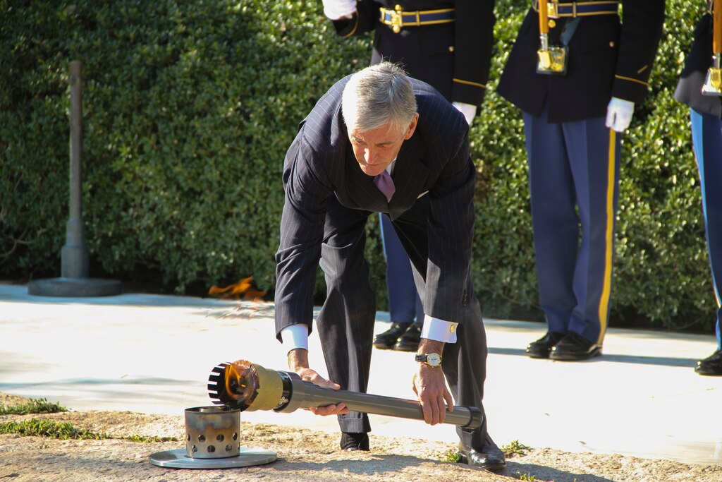 ARLINGTON, Va. -- Secretary of the Army John McHugh transfers the JFK Eternal Flame back to its permanent location on Oct. 29, 2013, after repair work to the site was completed. The flame underwent a full replacement of gas and airlines, received new digital controls and sensors, as well as a new burner assembly.