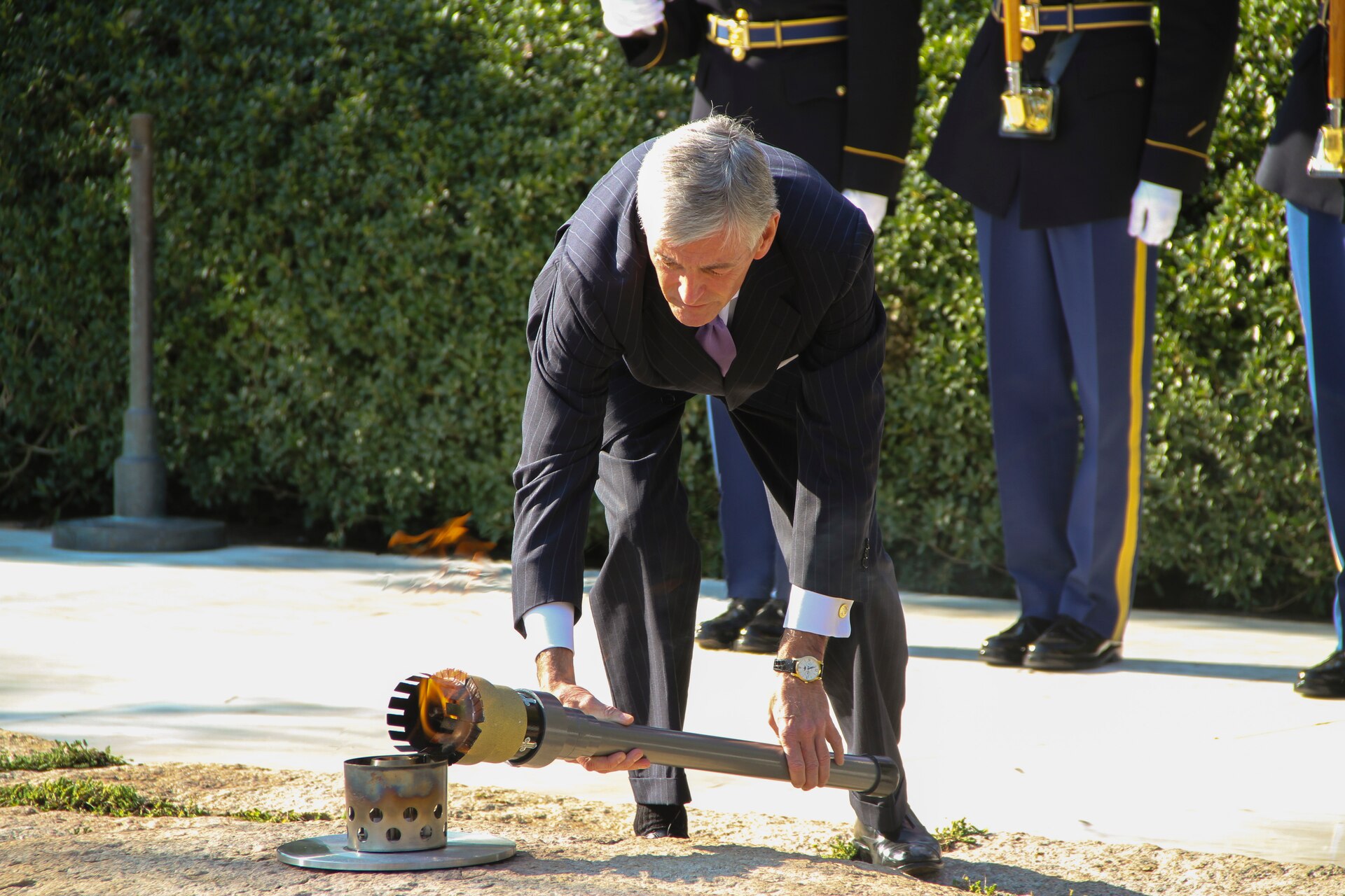 ARLINGTON, Va. -- Secretary of the Army John McHugh transfers the JFK Eternal Flame back to its permanent location on Oct. 29, 2013, after repair work to the site was completed. The flame underwent a full replacement of gas and airlines, received new digital controls and sensors, as well as a new burner assembly.