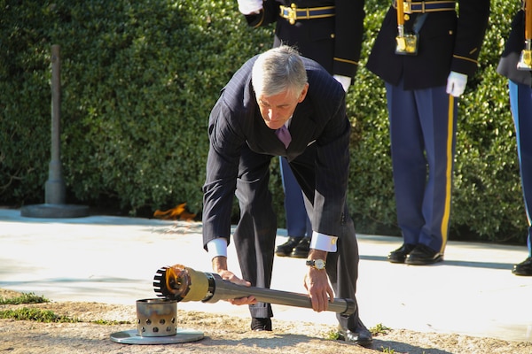 ARLINGTON, Va. -- Secretary of the Army John McHugh transfers the JFK Eternal Flame back to its permanent location on Oct. 29, 2013, after repair work to the site was completed. The flame underwent a full replacement of gas and airlines, received new digital controls and sensors, as well as a new burner assembly.