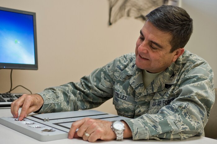 Col. (Dr.) Guillermo Tellez, 99th Medical Group commander, puts washers and pegs together as part of a pegboard test during the second annual occupational and physical therapy open house at the Mike O'Callaghan Federal Medical Center Oct. 29, 2013, at Nellis Air Force Base, Nev. This test was a part of a contest to see how many washers and pegs people could put together in 30 seconds. The winner of the event received a gift card. (U.S. Air Force photo by Senior Airman Matthew Lancaster)