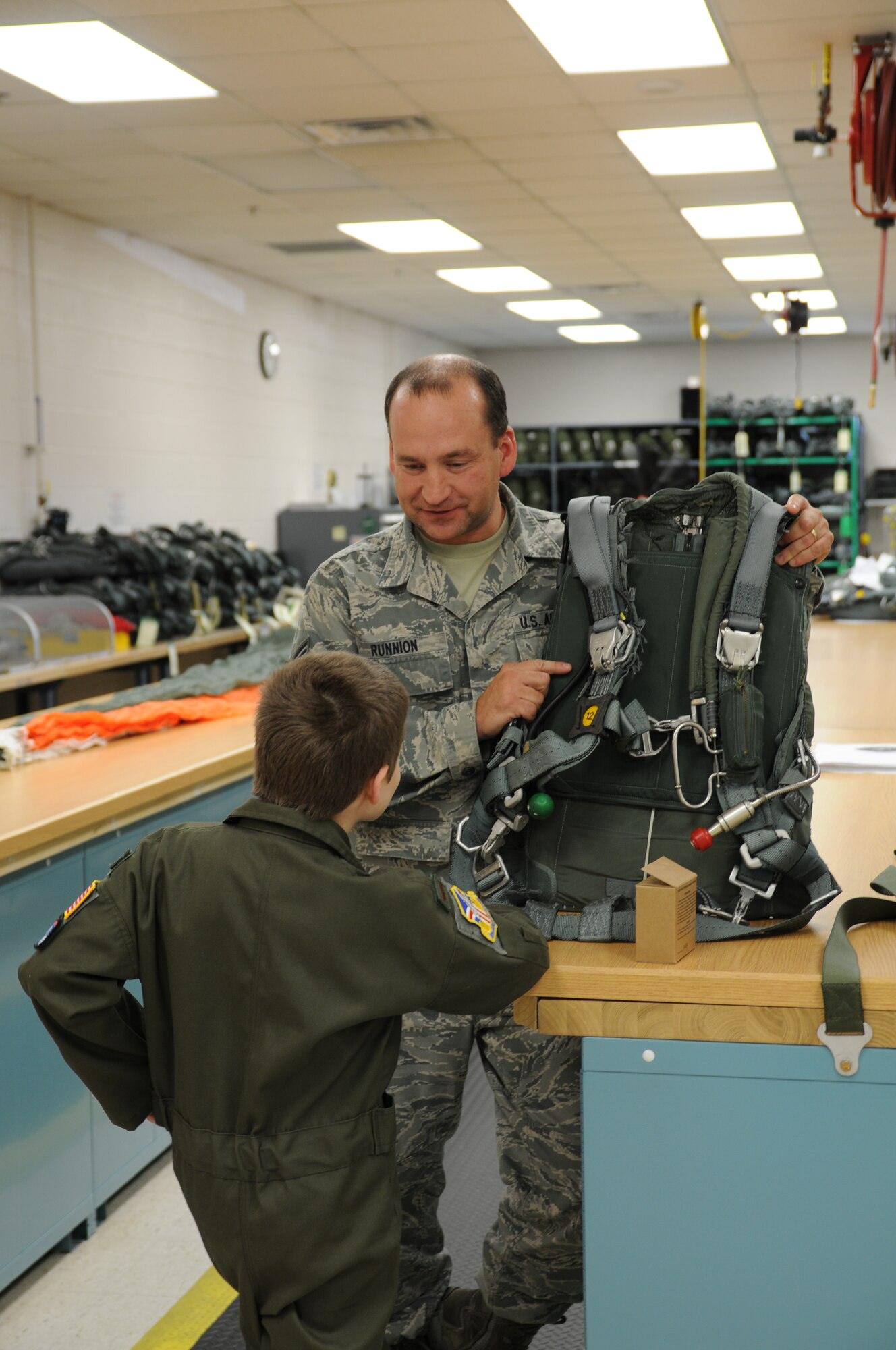 U.S. Air Force Reserve Technical Sgt. Charles Runnion, an Aircrew Flight Equipment Craftsmen with the 910th Operations Support Squadron, explains how a parachute works to Pilot for a Day and honorary 2nd Lieutenant Bruce Cellars here, Oct. 30, 2013. Bruce came to the Youngstown Air Reserve Station where he was enlisted as the 56th Pilot for a Day and an honorary 2nd Lieutenant. Bruce’s day included a base tour, high-speed taxi down the flight strip in a C-130H Hercules aircraft, a tour of the base fire department that included the chance to control a crash response truck water cannon and a Marine Corps Humvee shuttle, provided by the Marine Corps Reserve center here. The 910th Airlift Wing pilot for a day program began in 2000 to help bring a ray of sunshine into the lives of children being treated for chronic or life threatening conditions. U.S. Air Force photo by Mr. Eric M. White