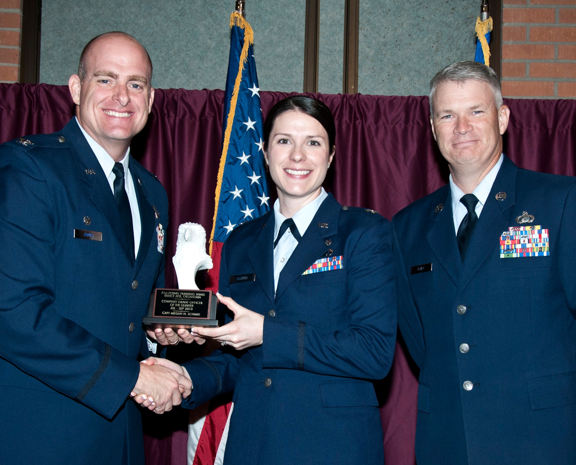 Capt. Megan Schmid with the 71st Flying Training Wing Staff Judge Advocate, center, is presented the Company Grade Officer of the Quarter award by Col. Darren James, 71st FTW commander, left, during a luncheon Oct. 22, at the Vance Collocated Club. To the right of Captain Schmid is Chief Master Sgt. Mark Aman, the 71st FTW command chief. (U.S. Air Force photo/ Terry Wasson)