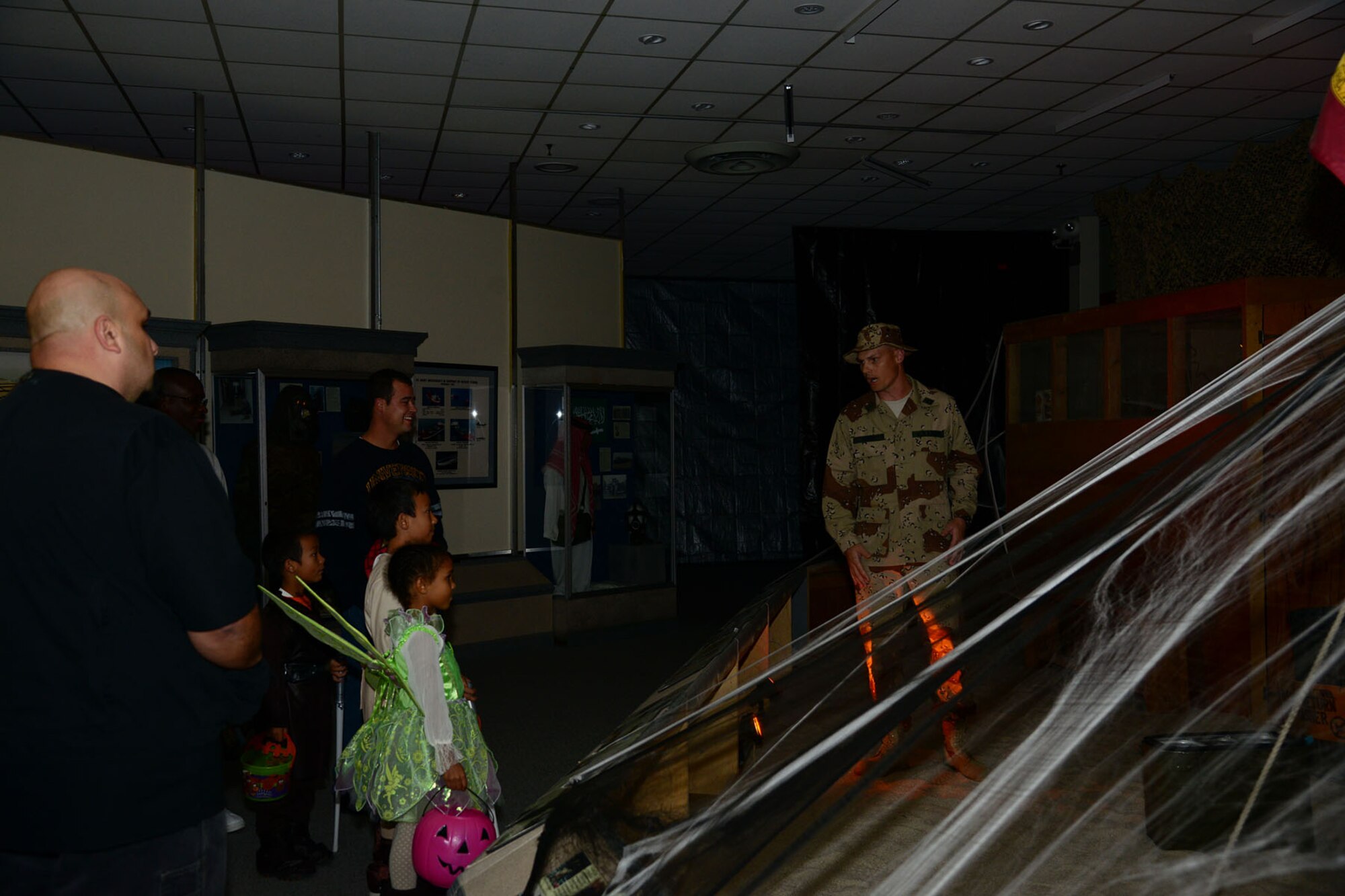 U.S. Army Sgt. 1st Class William Million, C Company, 1st Battalion, 210th Aviation Regiment instructor, right, interacts with trick-or-treaters at the Desert Storm exhibit during the U.S. Army Transportation Museum's "Night at the Transportation Museum" event at Fort Eustis, Va., Oct. 28, 2013. More than 30 volunteers dressed in battle uniforms of their respective exhibit’s era and handed out candy to trick-or-treaters. (U.S. Air Force photo by Staff Sgt. Ashley Hawkins/Released)