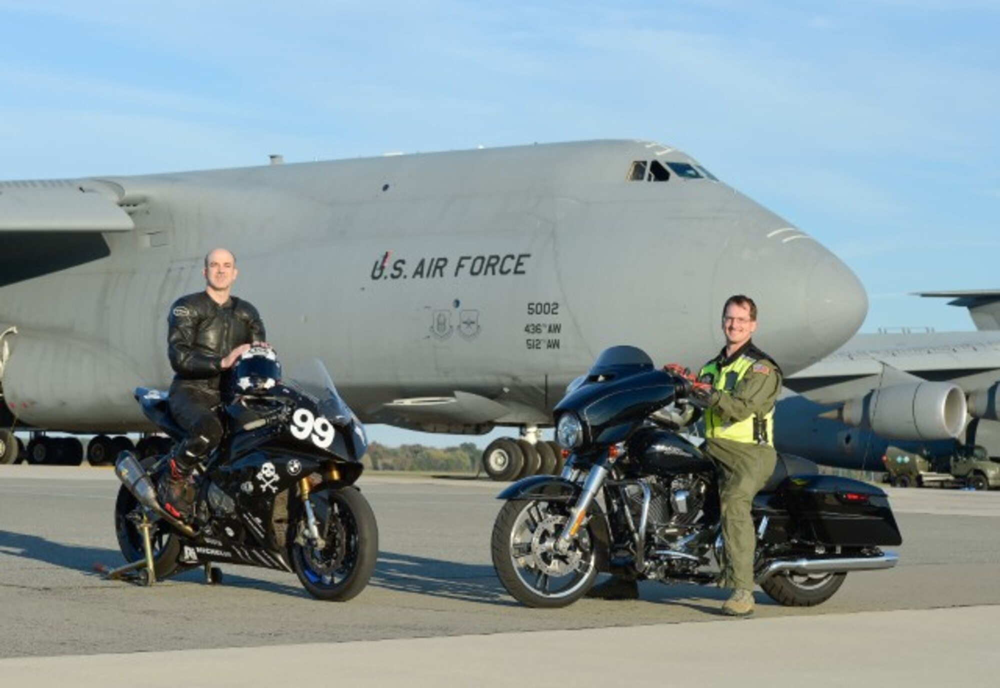 Sam Fleming, team leader of the Army of Darkness motorcycle endurance racing team, (left) sits on a BMW S1000RR, number 99, used by the team wearing full racing safety gear while Tech. Sgt. David Grant of the 3rd Airlift Squadron sits on a Harley Davidson Street Glide Special and wears mandatory safety gear for Air Force members and civilians during a visit to Dover Air Force Base, Del., on Oct. 21, 2013. (U.S. Air Force photo/Greg L. Davis)