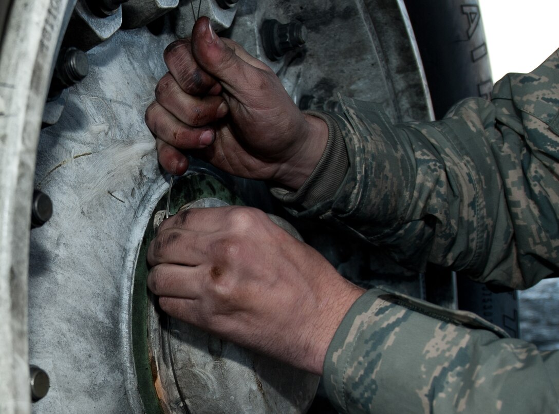 Airman 1st Class Cody Whitson, 28th Aircraft Maintenance Squadron crew chief, secures a hubcap to a B-1 tire with safety wire at Ellsworth Air Force Base, S.D., Oct. 24, 2013. Whitson learned how to perform a brake replacement as part of scheduled maintenance under the watchful eye of his trainer. (U.S. Air Force photo by Airman 1st Class Alystria Maurer/Released)