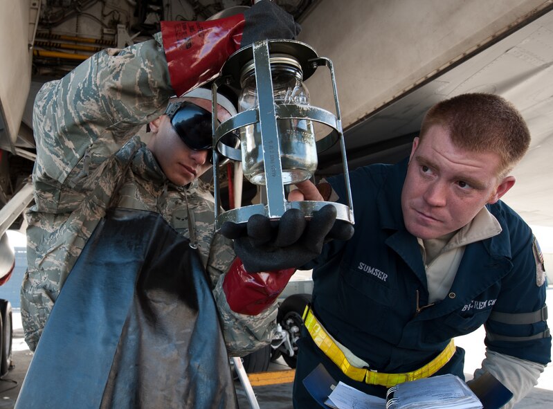 Airman 1st Class Peter Xiong (left) and Senior Airman Randall Sumser, 28th Aircraft Maintenance Squadron crew chiefs, examine fuel from a B-1 bomber at Ellsworth Air Force Base, S.D., Oct. 24, 2013. Sumser trained Xiong on how to perform the inspection to determine if there was anything wrong with the fuel sample. (U.S. Air Force photo by Airman 1st Class Alystria Maurer/Released)
