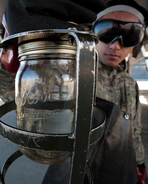 Airman 1st Class Peter Xiong, 28th Aircraft Maintenance Squadron crew chief, inspects a fuel sample from a B-1 bomber at Ellsworth Air Force Base, S.D., Oct. 24, 2013. There are 28 sump ports on each aircraft that must be tested to determine if the fuel contains debris, hydraulic fluid, water or other contaminants. (U.S. Air Force photo by Airman 1st Class Alystria Maurer/Released)