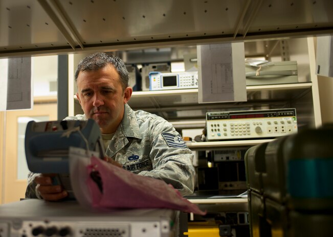 Tech. Sgt. Jeff Tucker, 57th Maintenance Squadron Precision Measurement Equipment Laboratory section supervisor, places a measurement scale awaiting calibration in the holding area Oct. 28, 2013, at the PMEL on Nellis Air Force Base, Nev.  Each piece of equipment is placed in the holding area for a minimum of four hours so it can adjust to the temperature of the laboratory before being calibrated. Some equipment that PMEL aligns, calibrate differently in hot or cool climates. (U.S. Air Force photo by Staff Sgt. Michael Charles)