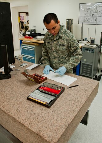 Senior Airman Daniel Lemier, 57th Maintenance Squadron Precision Measurement Equipment Laboratory journeyman, cleans a gauge block at the PMEL Oct. 28, 2013, at Nellis Air Force Base, Nev. If the gauge blocks are not regularly and thoroughly cleaned, residue will build up resulting in the blocks providing an inaccurate measurement when determining wiring length. (U.S. Air Force photo by Airman 1st Class Thomas Spangler)