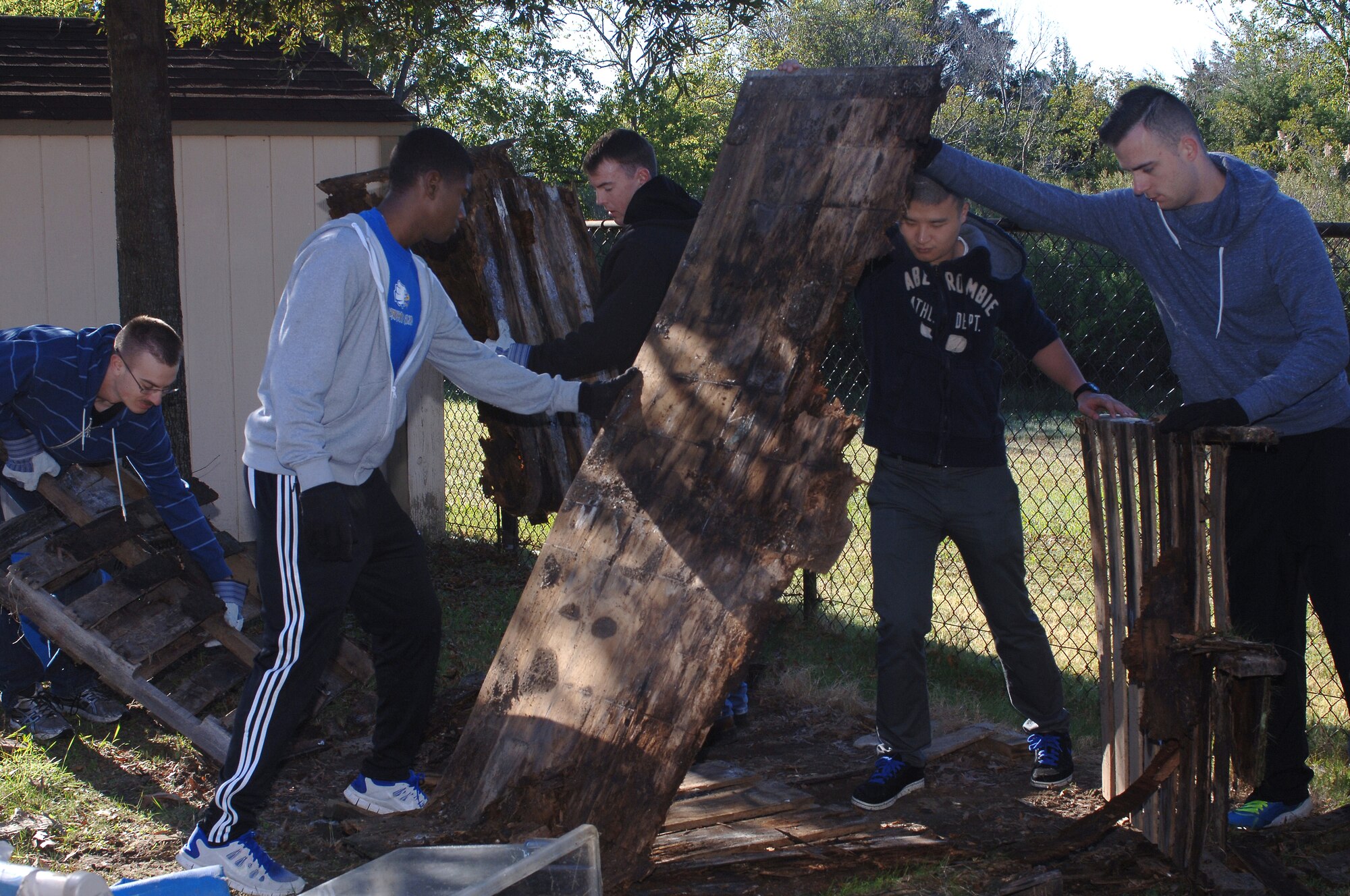 Airmen tear down damaged storage sheds at the Child Development Center at Langley Air Force Base, Va., Oct. 26, 2013. More than 40 Airmen volunteered to clean the surrounding area and make minor repairs to the CDC. (U.S Air Force photo by Senior Airman Teresa Aber/Released)