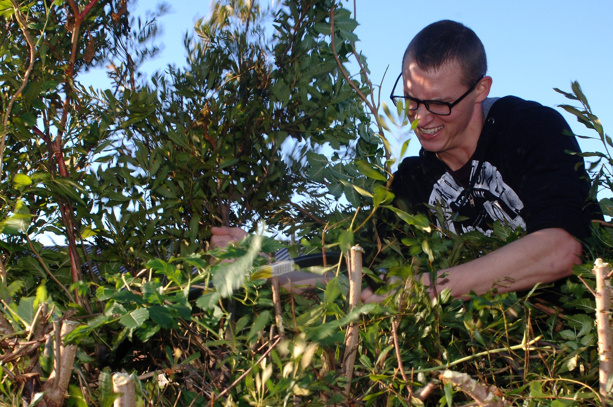 U.S. Air Force Airman 1st Class Caleb Shadle, 1st Maintenance Squadron aircraft armament systems apprentice, uses a handsaw to trim branches on trees at the Child Development Center at Langley Air Force Base, Va., Oct. 26, 2013.  Volunteers mowed grass, cut down trees and cleared debris to keep the area surrounding the CDC free of snakes and rodents. (U.S Air Force photo by Senior Airman Teresa Aber/Released)