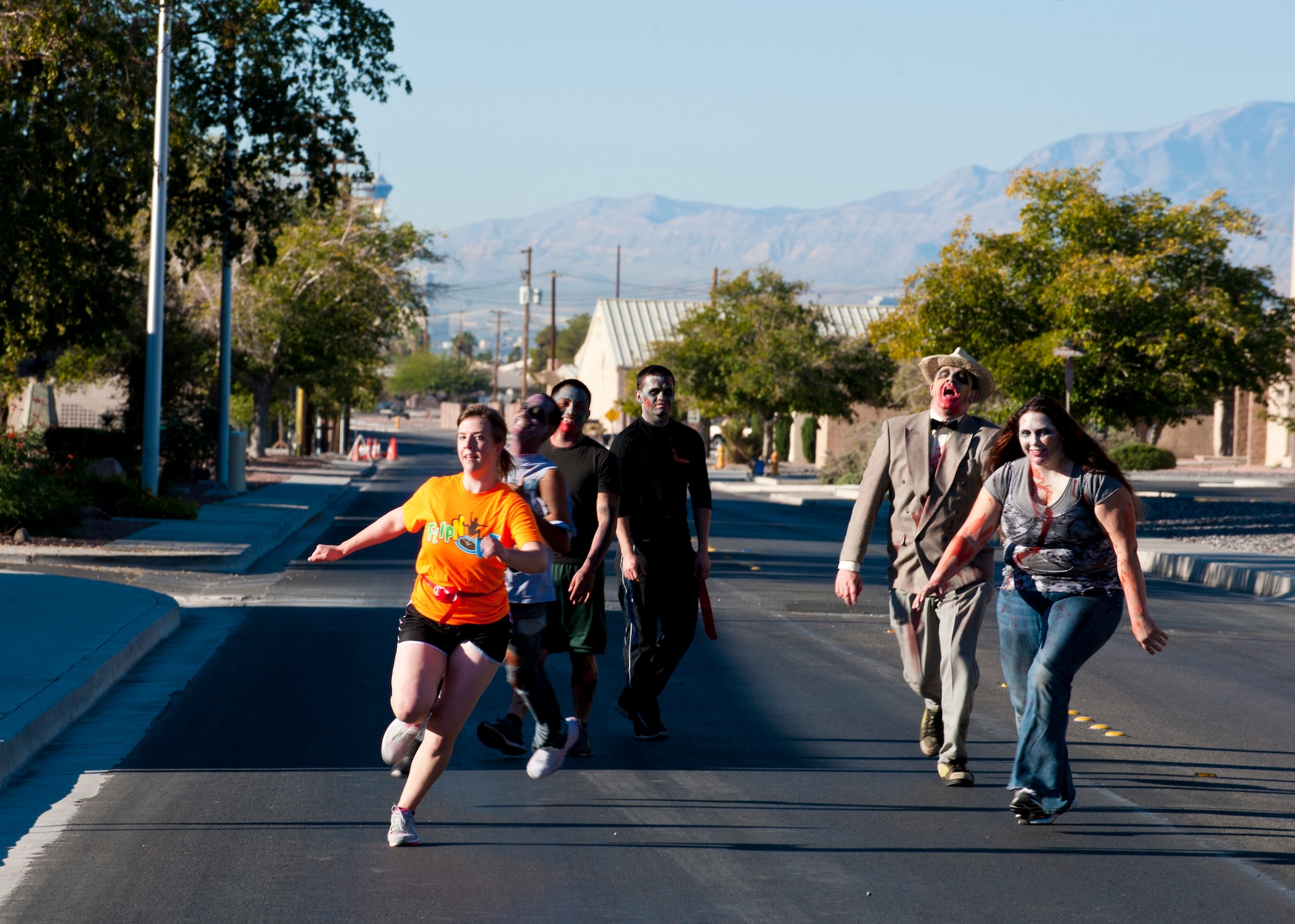 An airman from Creech Air Force Base, Nev., runs from zombies down Tyndall Road Oct. 26, 2013, at Nellis Air Force Base, Nev. The Zombie 5 kilometer Run, hosted by the Nellis and Creech AFBs’ Dorm Council, began at Freedom Park and concluded at the Nellis Sports Pavilion. Each participant wore flags similar to flag football during the run. At certain points runners were chased by zombies and forced to sprint as fast as they could to escape their clutches. If a runner’s flag was pulled, the participant was considered overtaken by the zombies. (U.S. Air Force photo by Airman 1st Class Thomas Spangler)