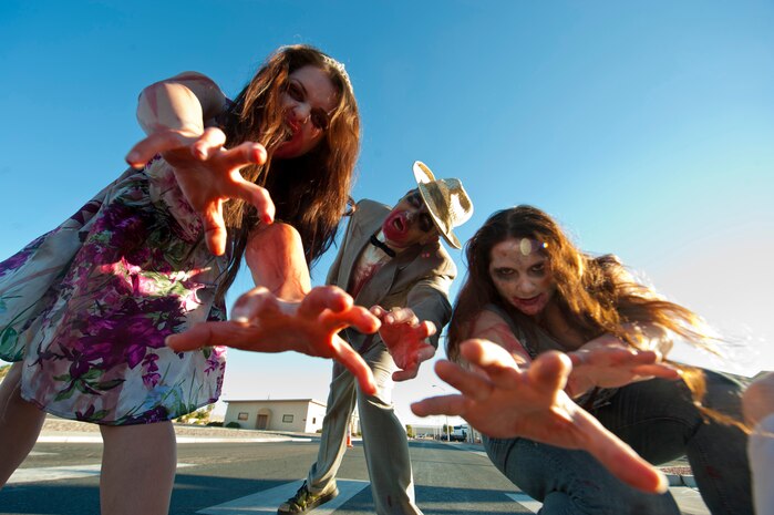 Airman 1st Class Caroline Rulison (left), Staff Sgt. Ryan Stafford (middle), and Staff Sgt. Sarah Schaan (right), all assigned to the 99th Aerospace Medical Squadron, dress as zombies and prepare to chase runners along Tyndall Road Oct. 26, 2013, at Nellis Air Force Base, Nev. The Airmen volunteered to play zombies during the Zombie 5 kilometer run, hosted by the Nellis and Creech AFBs Dorm Council, in celebration of Halloween. (U.S. Air Force photo by Airman 1st Class Thomas Spangler)