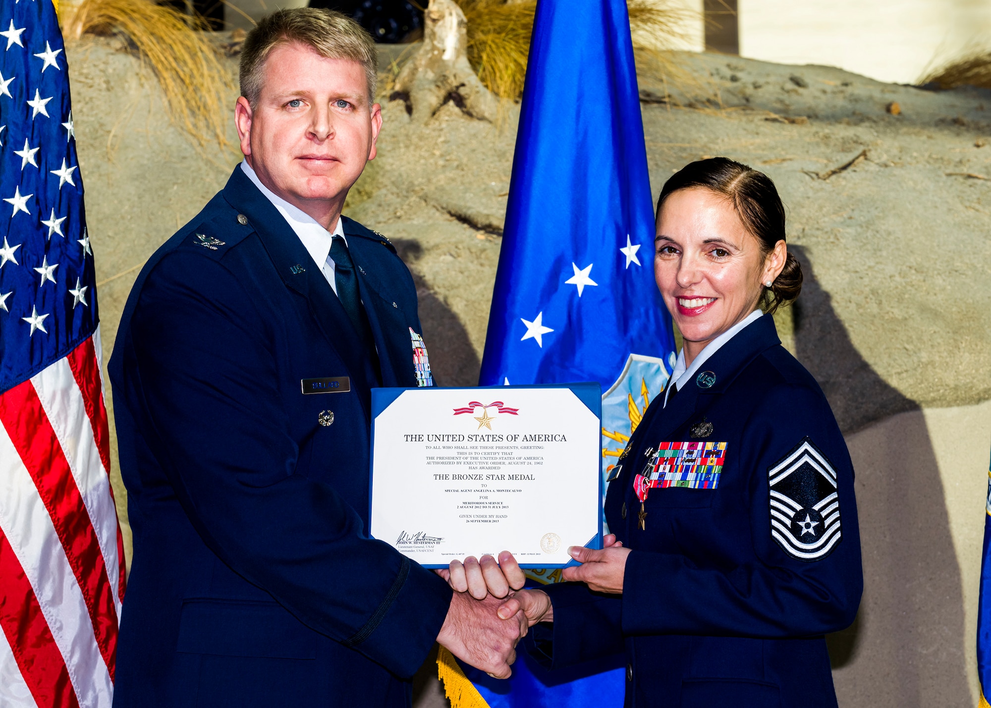 Special Agent Angelina Montecalvo receives her Bronze Star Medal citation from Col. Terry Bullard, OSI 2nd Field Investigations Region vice commander. Montecalvo received the medal for her work in Afghanistan as the 24th Expeditionary Field Investigations Squadron superintendent at Al Udeid Air Base, Qatar. (U.S. Air Force photo/Mike Hastings)