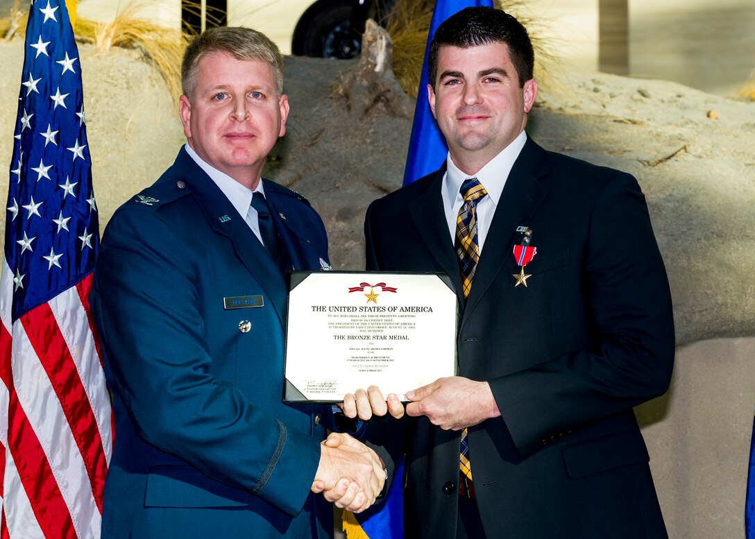 Special Agent Adam Lohman, right, receives his Bronze Star Medal citation from Col. Terry Bullard, OSI 2nd Field Investigations Region vice commander. Lohman received the medal for his work as the special agent in charge of OSI’s Expeditionary Detachment 2416, Shindand Air Base, Afghanistan. (U.S. Air Force photo/Mike Hastings)