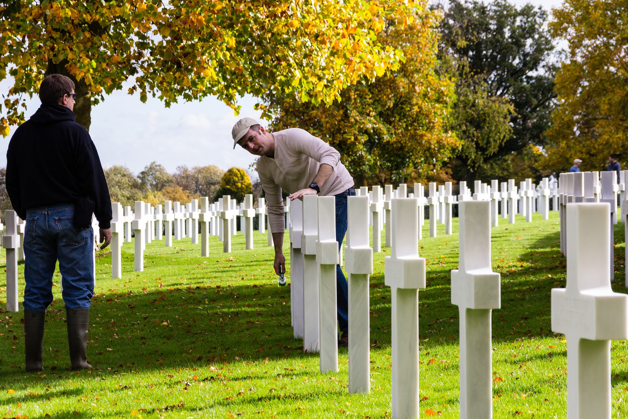 CAMBRIDGE, United Kingdom – (left to right) Kevin Miller and U.S. Air Force Master Sgt. Daniel Spencer, both the U.S. European Command Joint Intelligence Operations Center - Europe Analytic Center Eurasia Division, RAF Molesworth, check a Madingley American Cemetery headstone after cleaning it. Members of U.S. European Command Joint Intelligence Operations Center - Europe Analytic Center Eurasia Division joined with the RAF Alconbury Girl Scouts a to clean the headstones of American servicemen and women interred at the United Kingdom’s only World War II cemetery Oct. 26.