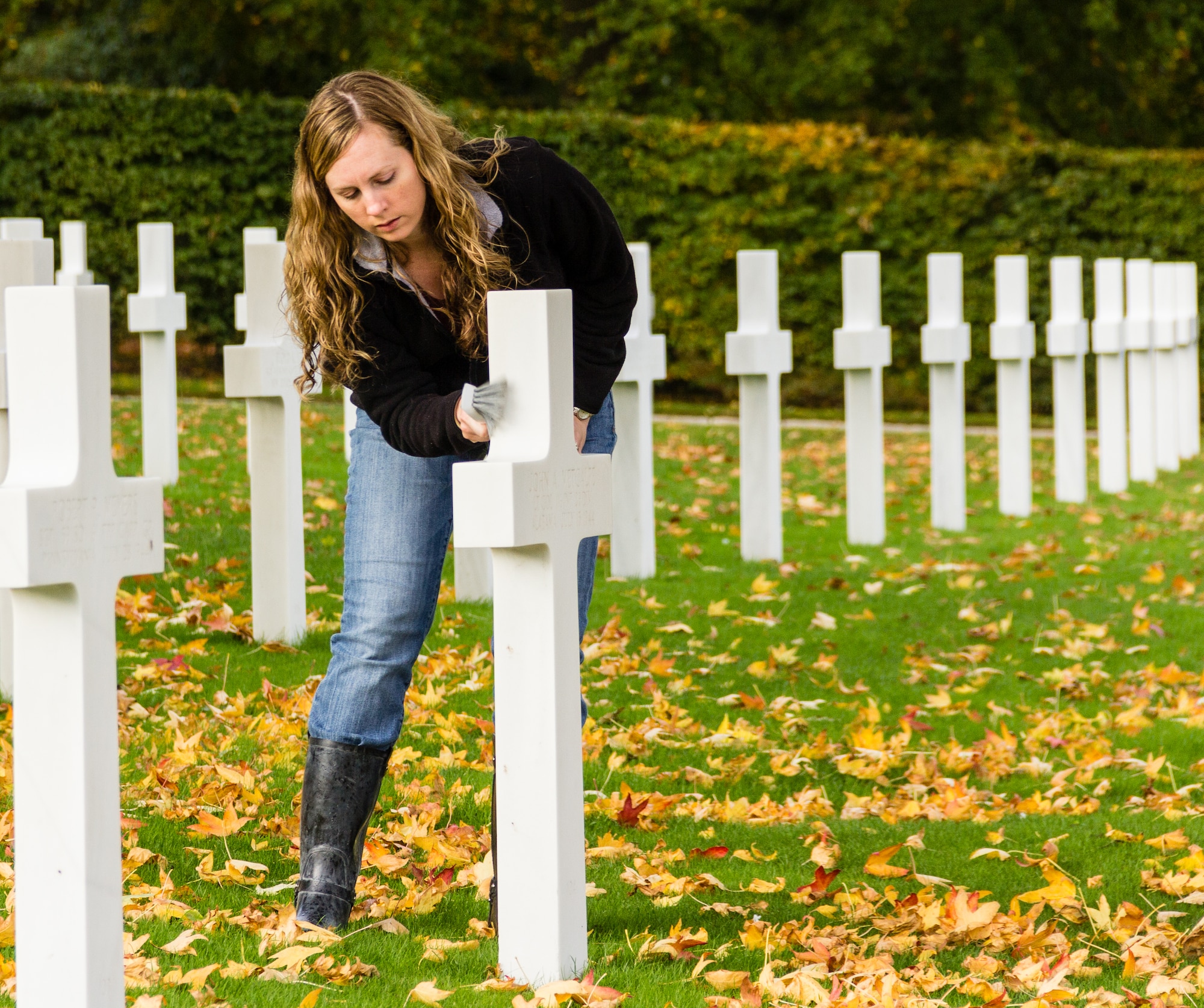 CAMBRIDGE, United Kingdom – U.S. Air Force 1st Lt. Katelynn Blasdel, U.S. European Command Joint Intelligence Operations Center - Europe Analytic Center Eurasia Division, RAF Molesworth, uses a brush to clean a headstone in Madingley American Cemetery. Members of U.S. European Command Joint Intelligence Operations Center - Europe Analytic Center Eurasia Division joined with the RAF Alconbury Girl Scouts a to clean the headstones of American servicemen and women interred at the United Kingdom’s only World War II cemetery Oct. 26.