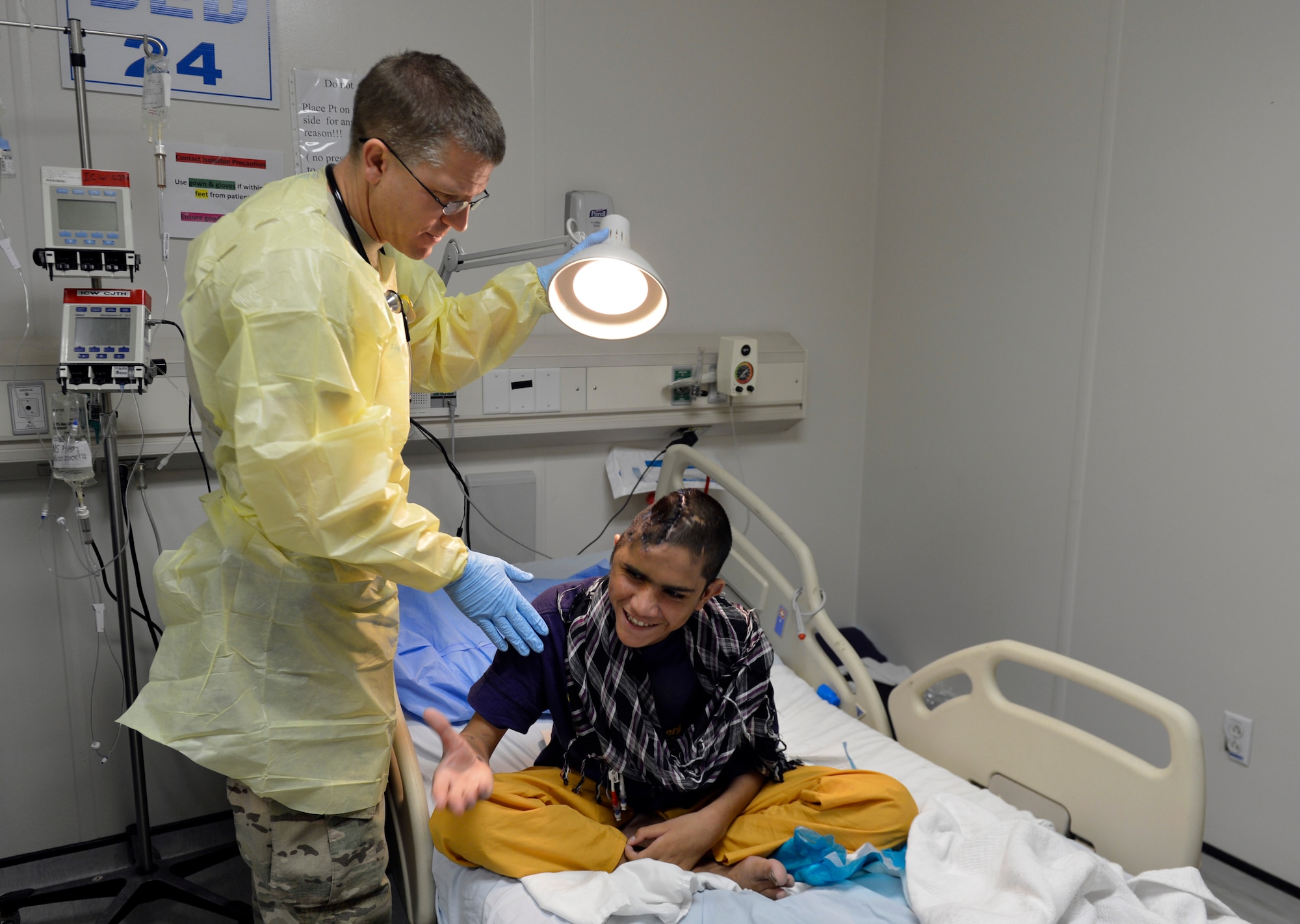 Lt. Col. David Jones, 455th Expeditionary Medical Group pediatrician, prepares to examine a 12-year-old boy’s head in the Craig Joint Theater Hospital on Bagram Airfield, Afghanistan, Oct. 20. The boy recently had a surgery to remove infected skull and brain abscesses.  Jones is a native of San Antonio, Texas. (U.S. Air Force photo/ Staff Sgt. Stephenie Wade)