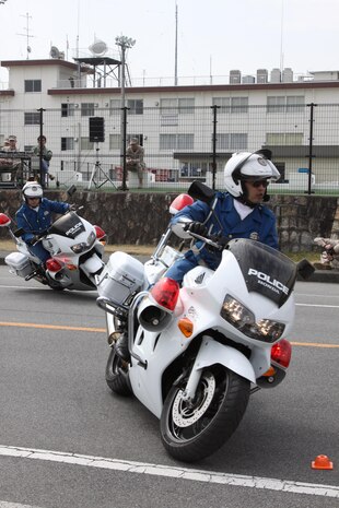 Iwakuni police officers show off their motorcycle riding skills during the safety demonstration at the road adjacent to the outdoor pool March. 22. One of the mototrcycle demonstrations displayed the differences of rear-wheel braking, front-wheel braking and all-wheel braking.