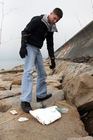 Volunteer Bryan J. Cowin stares down at the trash that has been washed ashore on the seawall north of Penny Lake aboard Marine Corps Air Station Iwakuni April 20, 2012. April 22 was established as International Earth Day in 1970 by the United Nations.