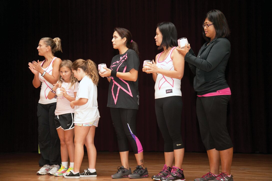 Family members of breast cancer victims hold candles to celebrate the lives of those lost to the illness Oct. 25 at the Camp Foster Community Center. The candles were part of the Zumba Xtravaganza, an event dedicated to educating men and women about breast cancer awareness and early prevention and detection. (U.S. Marine Corps photo by Lance Cpl. Natalie M. Rostran/Released)