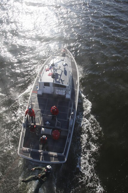 Seaman Justin M. Jones, a search and rescue medical technician with Marine Transport Squadron 1, is hoisted down to a Coast Guard utility boat during training Oct. 24.
