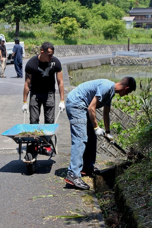 Lance Cpls. Jonathan Garcia-Carabajal, Marine Aviation Logistics Squadron 12 aviation ordnance systems technician, and Luis Olvera, MALS-12 flight equipment technician, clean up a water way that feeds into the local rice fields during the Marine Lounge Futashika River clean up, May 18. The cleanup is only one of many volunteer opportunities available.